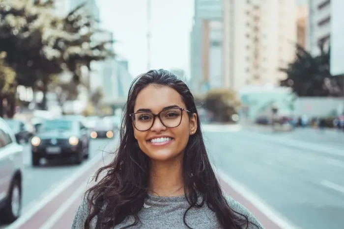 A portrait photo of a smiling young woman with long, dark, wavy hair.
