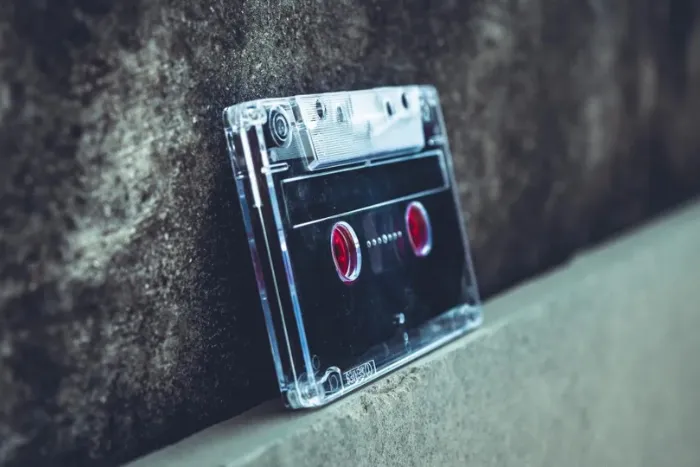 A clear plastic audio cassette tape with dark tape visible inside.