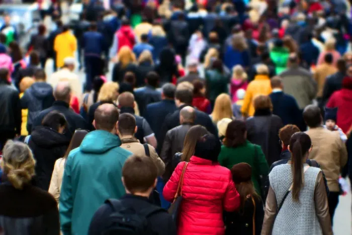 Crowd of people walking in the same direction on a street or pedestrian area.