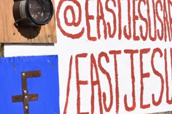 A blue square with a brown 'F' likely for Facebook decorated with metal rivets, a metal cylinder/lens mounted on wood.